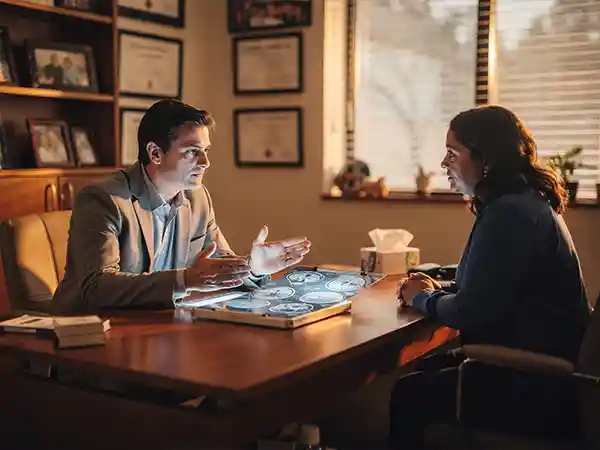 Pediatric neurologist explaining brain MRI findings to a parent during a cerebral palsy consultation
