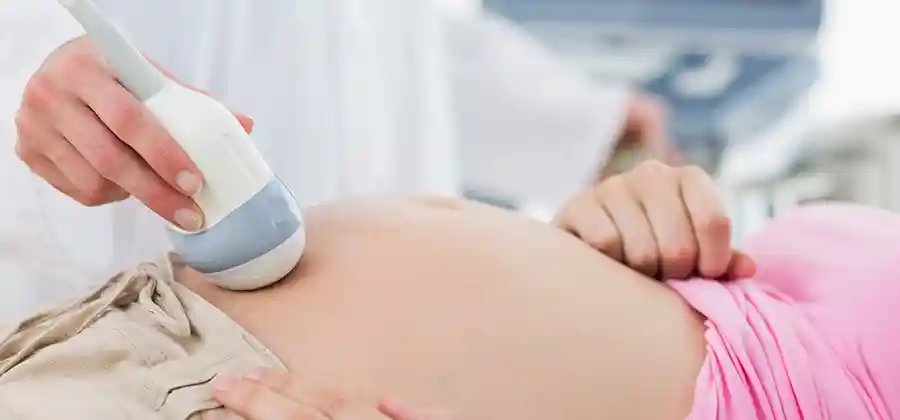 Pregnant mother receiving prenatal care to reduce cerebral palsy risk factors including monitoring and infection screening
