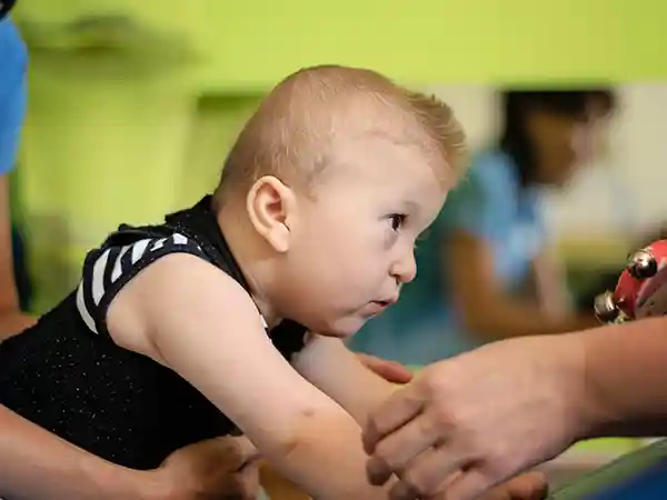 Parent monitoring baby for early signs of cerebral palsy including muscle tone and movement patterns