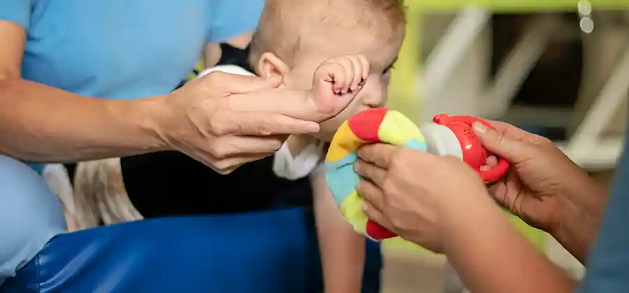 Toddler with cerebral palsy symptoms working on developmental milestones with a physical therapist