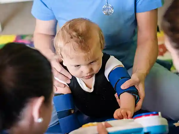 Multidisciplinary therapy team including physical therapist and occupational therapist working with a child with cerebral palsy