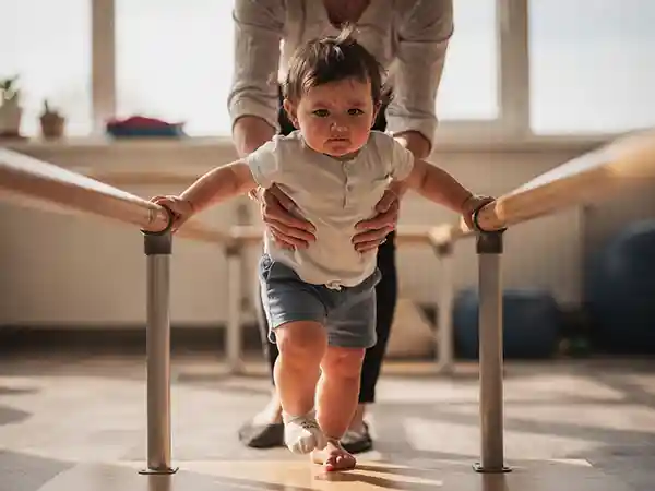 Toddler practicing assisted walking with a pediatric physical therapist