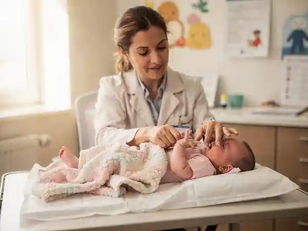 Pediatrician carefully examining an infant's muscle tone and reflexes during a developmental check, with a parent observing