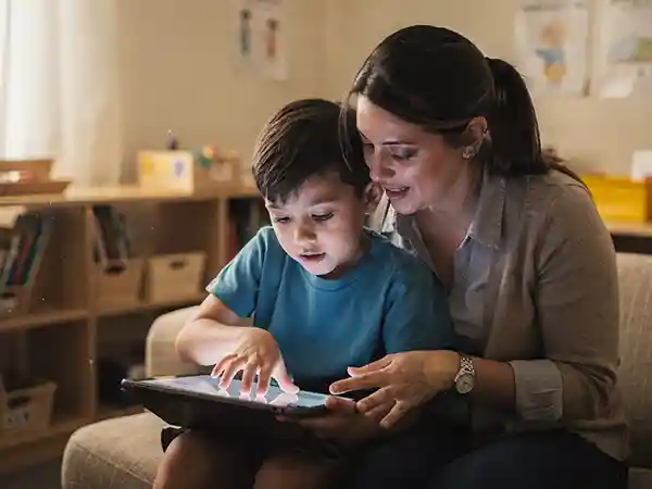 Developmental specialist working one-on-one with a school-age child using communication and learning tools to address non-motor symptoms of cerebral palsy
