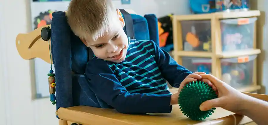 Child with cerebral palsy working with an occupational therapist on fine motor skills and daily living activities
