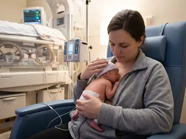 Parent doing kangaroo care with their premature baby in the NICU, demonstrating skin-to-skin contact during specialized neonatal care